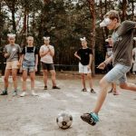 Teenagers enjoying an outdoor soccer game with a humorous twist using eyecovers as a challenge.